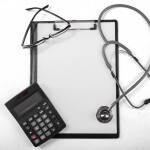 מחשבון, לוח כתיבה וסטטוסקופ של רופא העוסק בועדה רפואית לקביעת גמלת נכות מעבודה